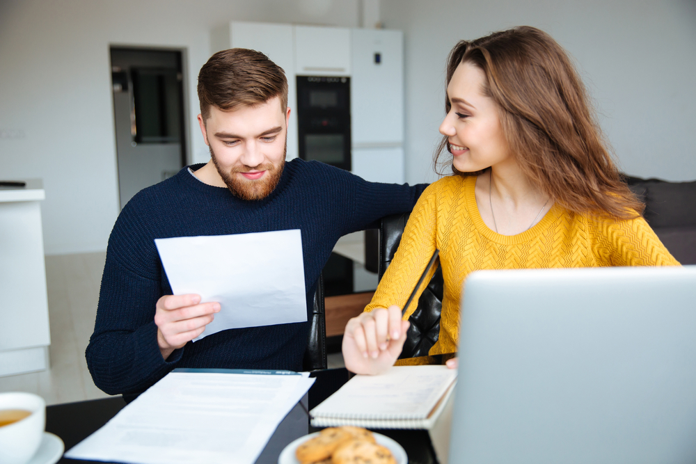 Happy young couple calculating bills at home-1